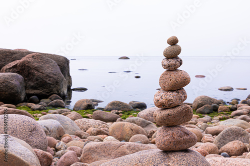 Pyramid of granite stones or rocks on the coast of the sea, ocean or on the beach of the lake or river in the summer or autumn sunny day. Vivid, bright and colorful marine landscape or view