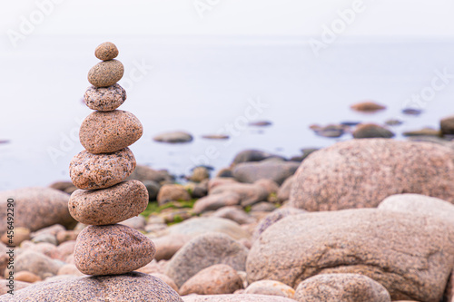 Pyramid of granite stones or rocks on the coast of the sea  ocean or on the beach of the lake or river in the summer or autumn sunny day. Vivid  bright and colorful marine landscape or view