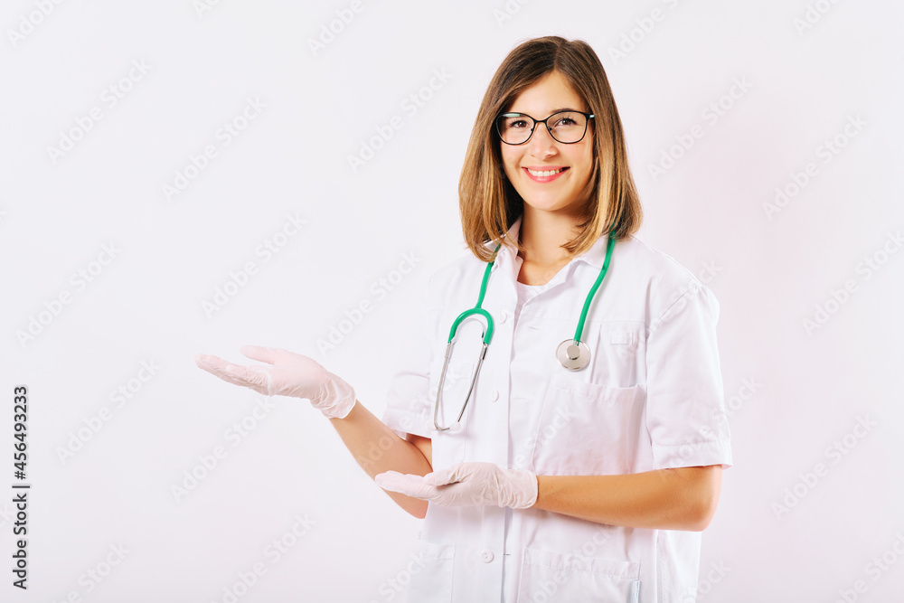 Studio portrait of young female doctor posing on white background, pointing aside with hands Studio portrait of young female doctor posing on white background, pointing aside with hands