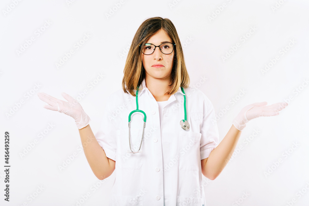 Studio portrait of young female doctor with clueless and confused fasial expression, spreading arms to the different sides Studio portrait of young female doctor with clueless and confused fasial expression, spreading arms to the different sides
