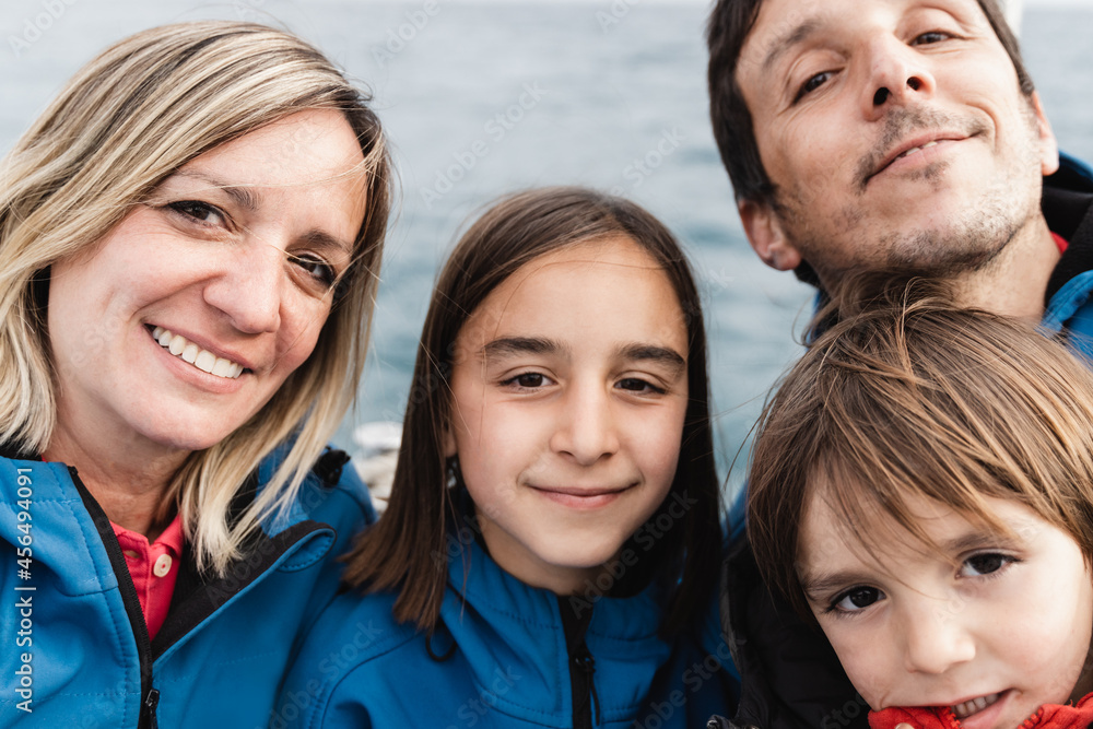 Fototapeta premium Happy family doing selfie with mobile phone at luxury boat with ocean on background - Hapinness, joy and love concept - Focus on mother face