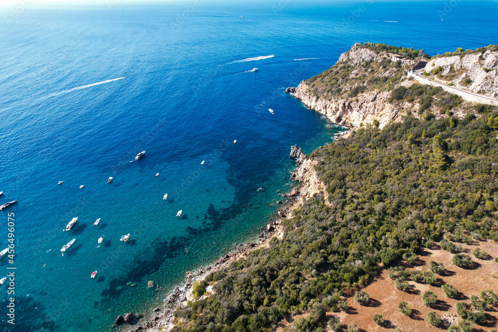 View from above, stunning aerial view of a bay with boats and luxury yachts sailing on a turquoise, clear water surrounded by cliffs. Porto Santo Stefano, Monte Argentario, Italy.