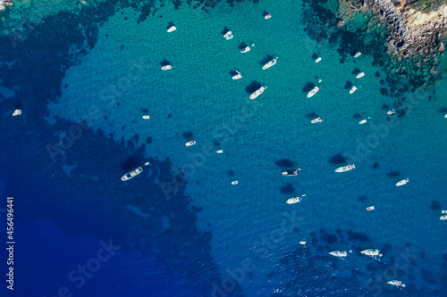 View from above, stunning aerial view of a bay with boats and luxury yachts sailing on a turquoise, clear water. Porto Santo Stefano, Italy.