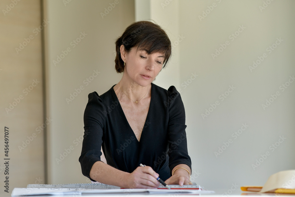 Portrait of a female architect sitting at her desk working on a new construction project Portrait of a female architect sitting at her desk working on a new construction project