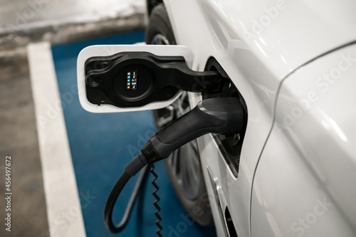 Hybrid electric car vehicle charging with pump inserted in charging socket parked waiting to be charged up. Modern technology automobile transport innovation, eco environmental energy for planet.
