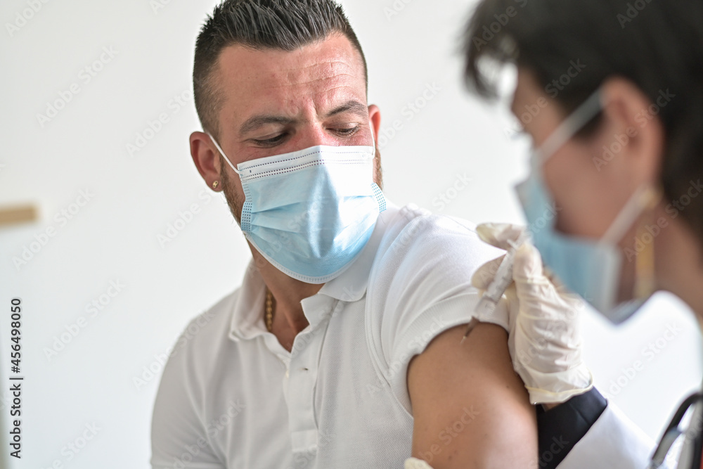 Injection of the vaccine against the covid-19 by a female doctor  in his medical office