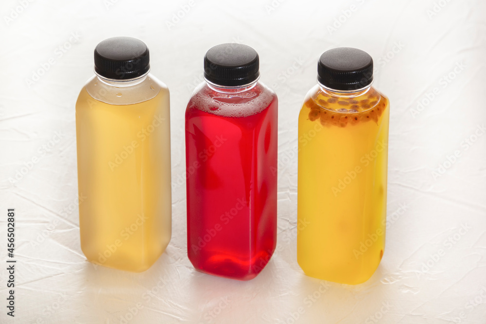 Three plastic bottles with fruit fruit drinks in red and yellow stand on a white table Three plastic bottles with fruit fruit drinks in red and yellow stand on a white table