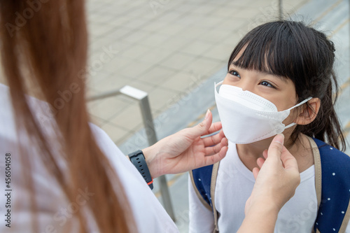 Asian mother helps her daughter wearing a medical mask for protection Covid-19 or coronavirus outbreak prepare to go to school when back to school order.