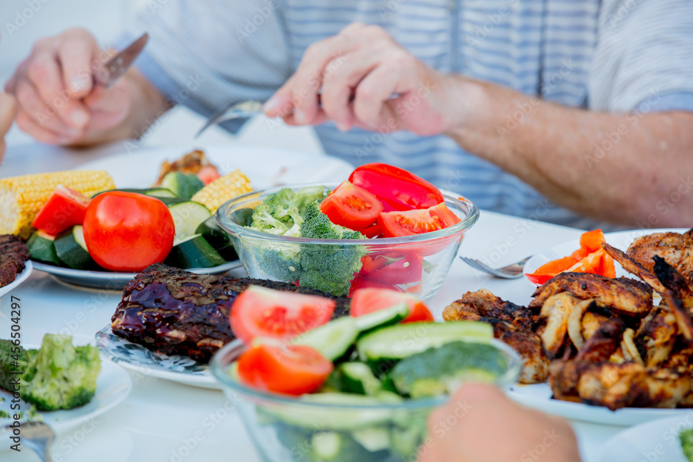 people sitting at table and eating grilled chicken wings and vegatebles people sitting at table and eating grilled chicken wings and vegatebles