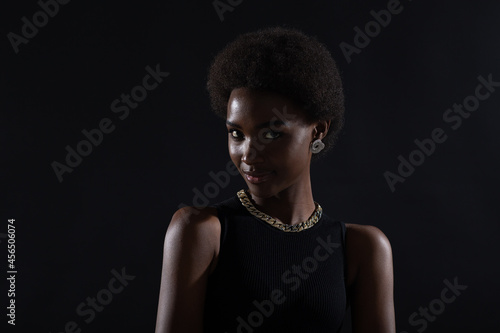 Close up portrait of african american woman with afro hairstyle on black studio background backlit