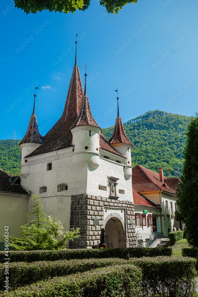 Fototapeta premium Red Spires on red tiled roof of Catherines gate, entrance to medieval city of Brasov Romania