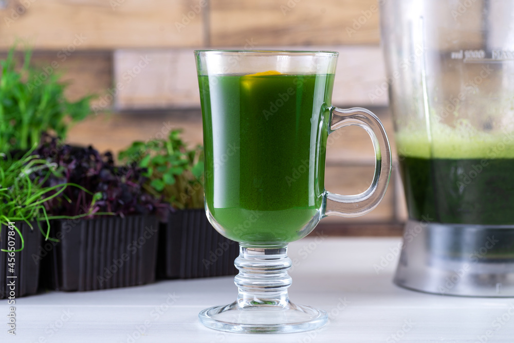 Microgreen juice on the kitchen table. Micro greens in a blender. Make a microgreen smoothie at home. Healthy and organic food Microgreen juice on the kitchen table. Micro greens in a blender. Make a microgreen smoothie at home. Healthy and organic food