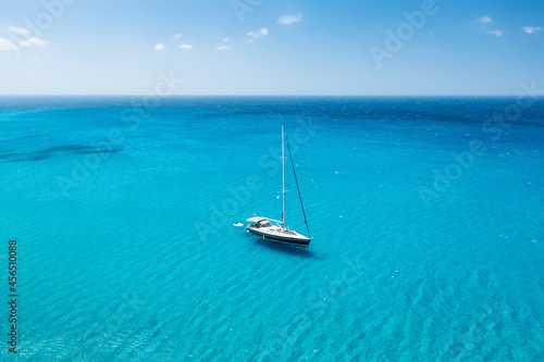 An aerial view of the yacht on the azure sea. Transparent clear water in the Mediterranean Sea. Summer vacations and travels on a sailing yacht. Summer relaxation.