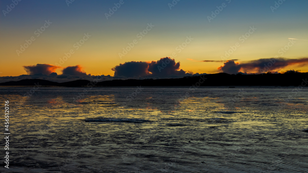 A golden sunset reflecting over the mudflats of Kirkcudbright Bay in winter