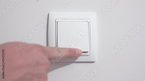 4K images of power consumption, video of a man's hand turning a wall switch on and off photo
