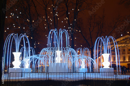 Beautiful artificial fountain with evening illumination in winter in the city photo