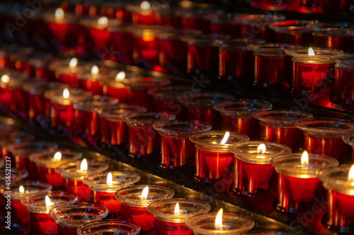 Obraz na plátne Selective focus of offering of red candles inside the church, Burning wax candlelight in the dark, Flame with warm light tone with black background