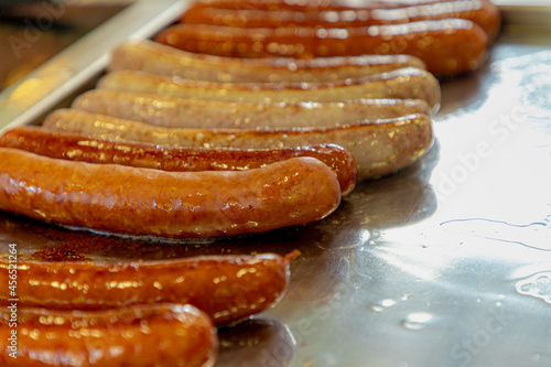 Photography An Austrian hot dog (bratwurst) Selective focus of long sausages grilling on the pan with oil in market, Street and takeaways food in urban of Vienna, Austria