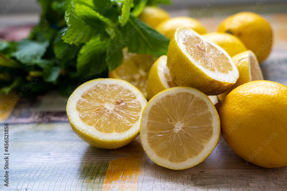 Group of wet lemons halves with mint leaves, on wooden colored table. close-up Group of wet lemons halves with mint leaves, on wooden colored table. close-up