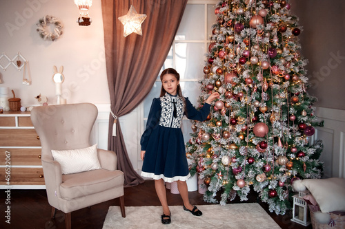 Cute beautiful girl in a smart dress in the Christmas room interior. New Year and Christmas concept