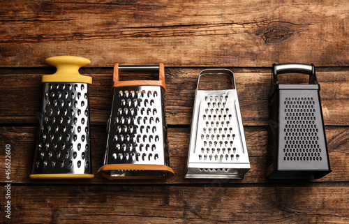 Different modern graters on wooden table  flat lay