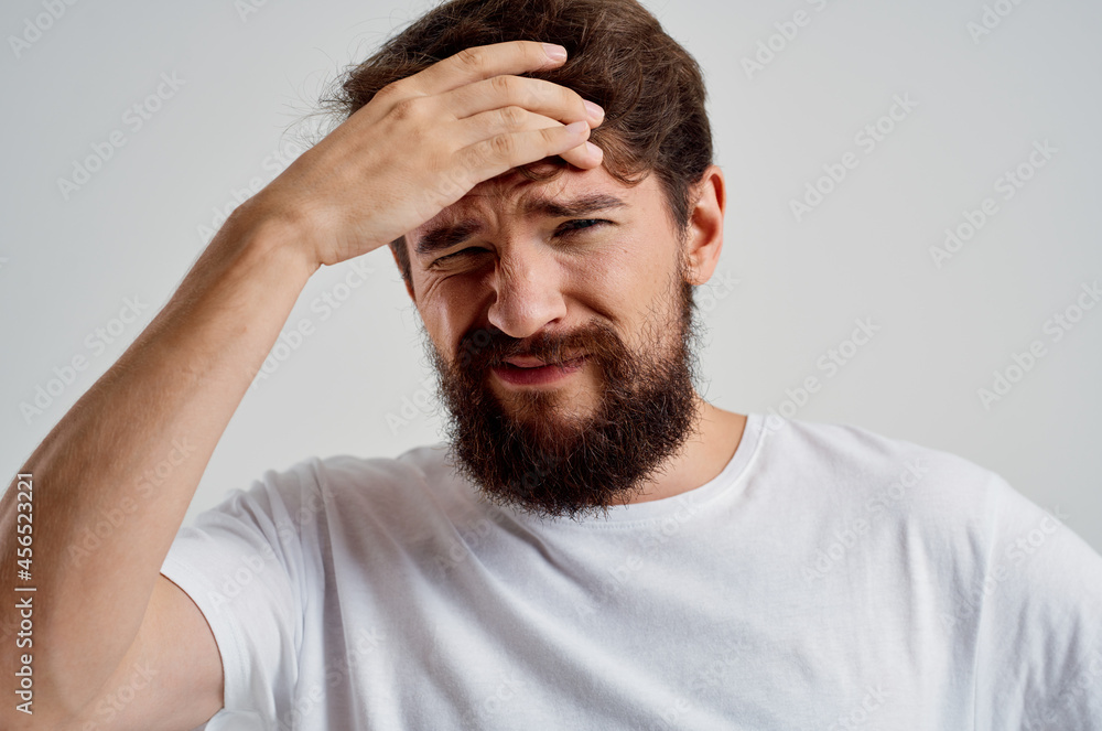 bearded man holding his head pain stress emotions light background bearded man holding his head pain stress emotions light background