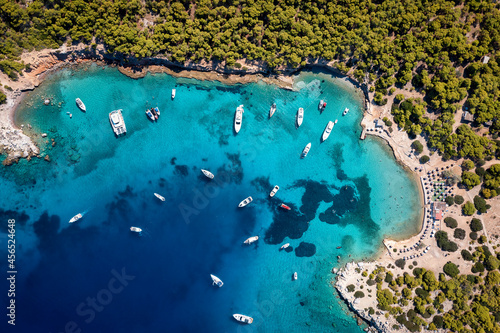 Aerial top down view of the many boats moored at the popular beach  of Moni island, Aegina, Saronic Gulf, Greece with turquoise sea and lush, green hills photo