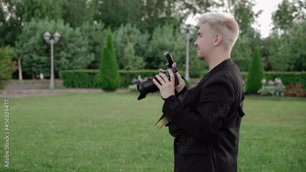 Male photographer takes photos on a professional camera outdoors in park. Male photographer takes photos on a professional camera outdoors in park.
