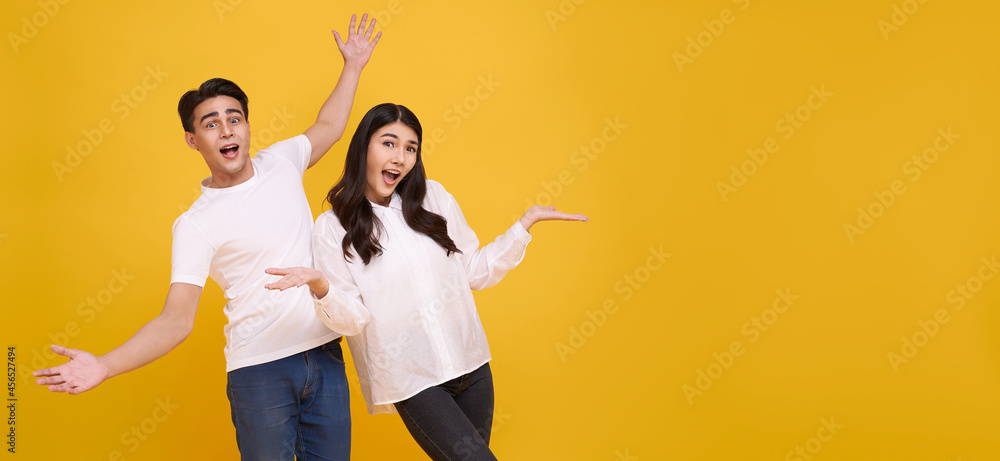 Naklejka premium Surprise young Asian couple man and woman happy and amazed on panoramic yellow background..