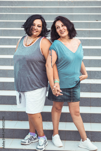 Portrait of two adult brunette twin sisters. Different styles