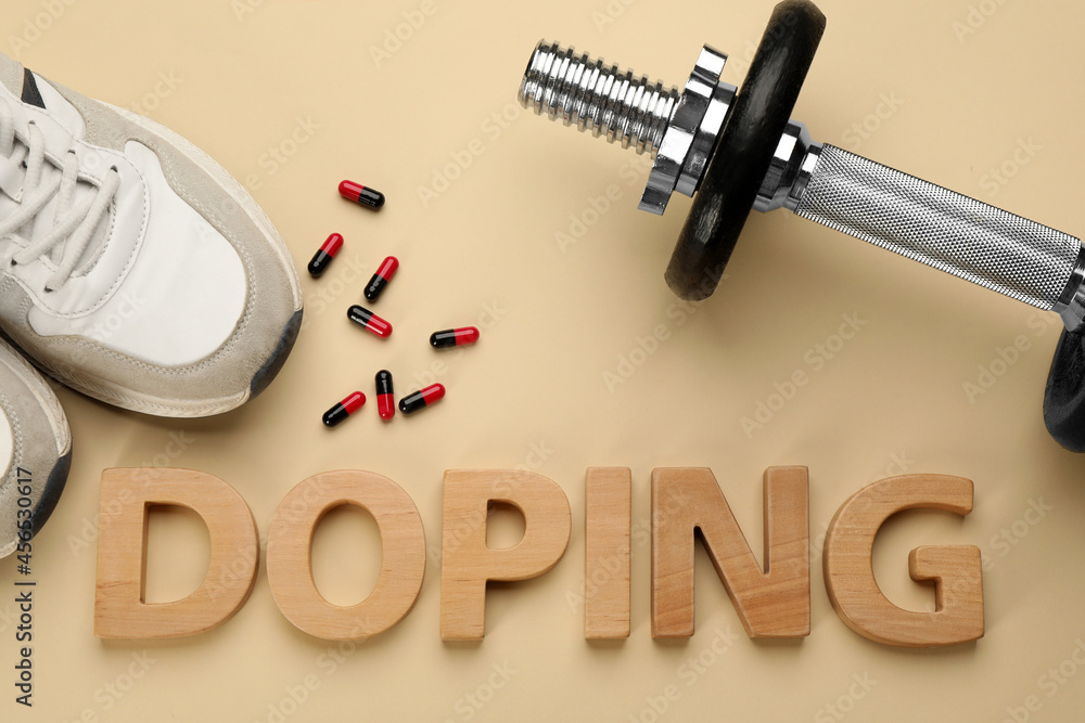 Word Doping, drugs, dumbbell and sport shoes on beige background, flat lay Word Doping, drugs, dumbbell and sport shoes on beige background, flat lay