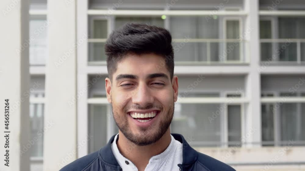 Portrait of a smiling young handsome man standing in front of corporate building looking at camera. High quality 4k footage Portrait of a smiling young handsome man standing in front of corporate building looking at camera. High quality 4k footage