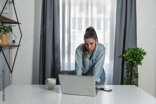 Young business woman waiting for internet connection in her home office to make a video call to her client
