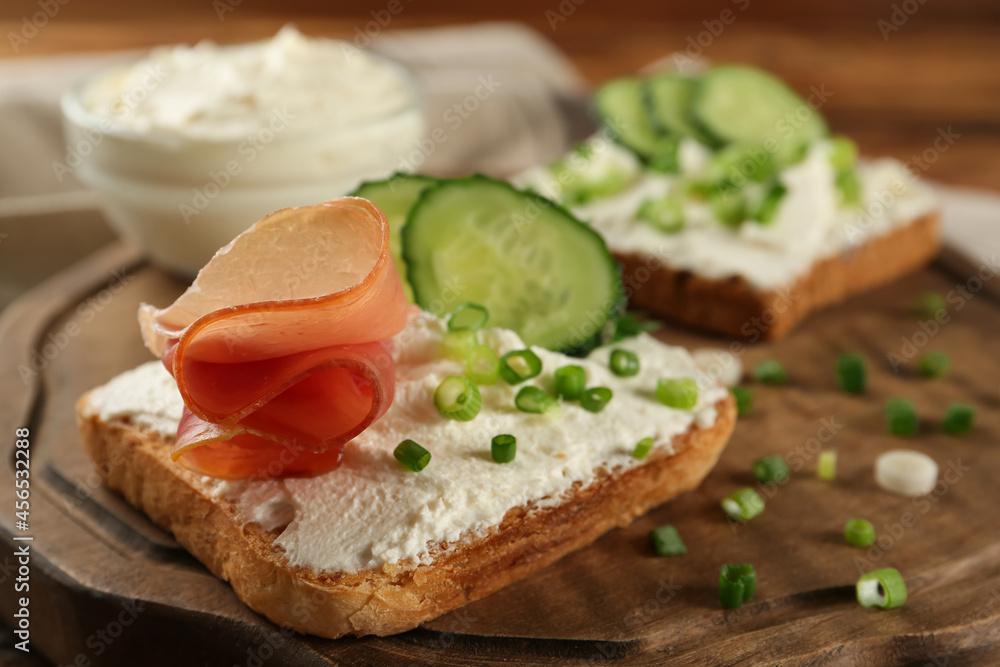 Delicious sandwiches with cream cheese and other ingredients on wooden board, closeup Delicious sandwiches with cream cheese and other ingredients on wooden board, closeup