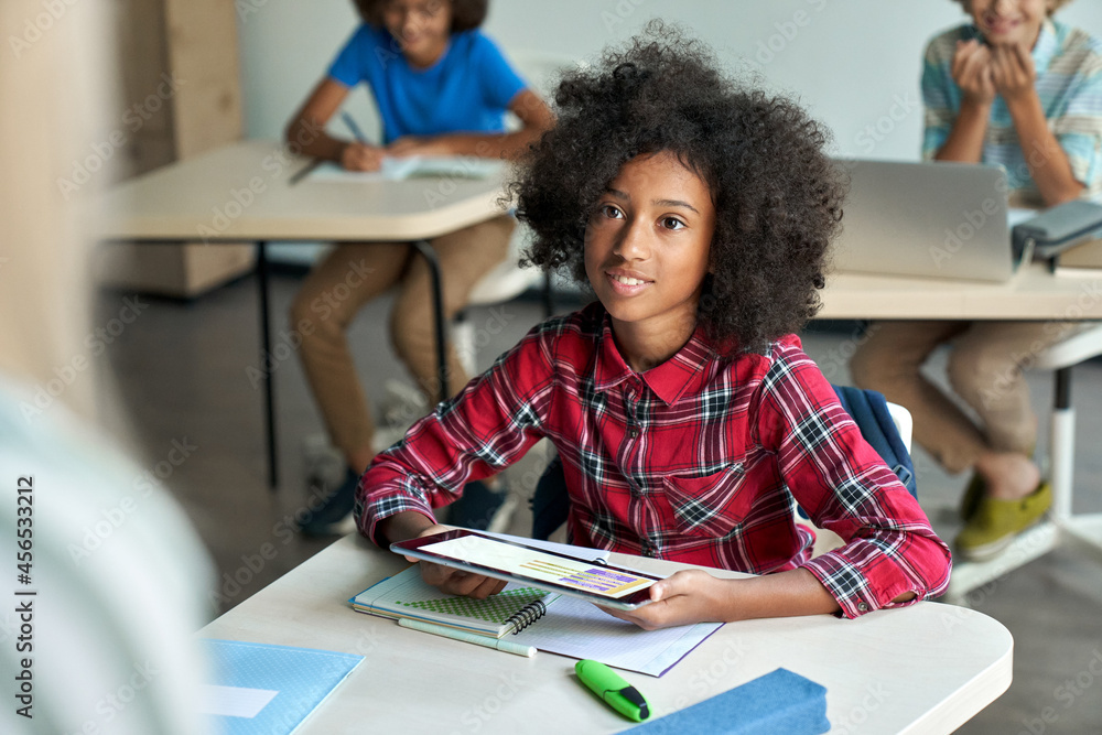 Happy African American schoolgirl looking listening to teacher using ...