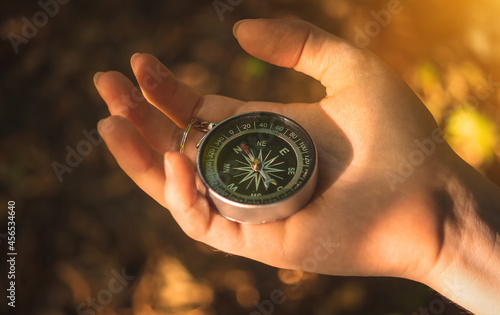 Nature orientation concept. Fenale hand with compass in the forest background photo photo