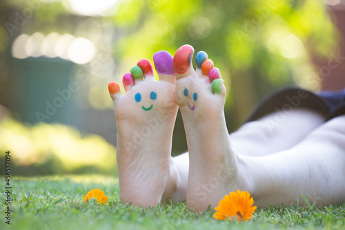 Children's feet with a pattern of paints smile on the green grass. © erika8213