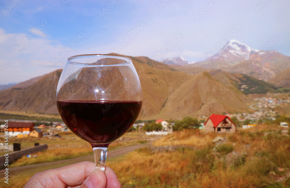 Closeup a Glass of Red Wine in Man's Hand Against Mountain Ranges