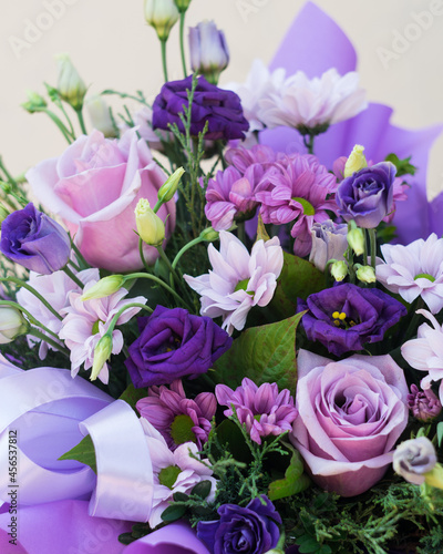 Bouquet of flowers in purple hat box on a light background, close-up, selective focus © Olga