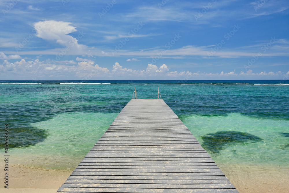 Sandy wooden dock stretches out into the crystal clear and warm waters of the Carribean  in the Cayman Islands