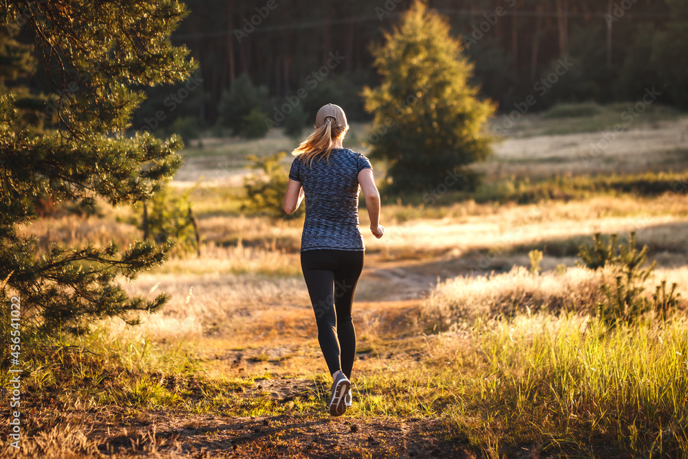 Woman running in nature during sunset. Female runner jogging outdoors. Sport training and active lifestyle. Cross-country running Woman running in nature during sunset. Female runner jogging outdoors. Sport training and active lifestyle. Cross-country running