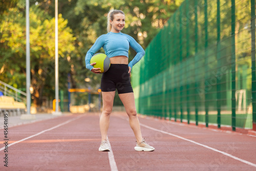 Young athletic woman in sportswear with medicine ball at the stadium