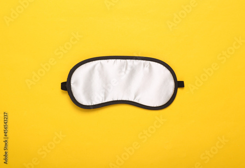Sleep mask on yellow background. Top view, flat lay. Concept of vivid dreams. Accessories for sleep. Minimal style.