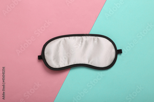 Sleep mask on pink blue background. Top view, flat lay. Concept of vivid dreams. Accessories for sleep. Minimal style.