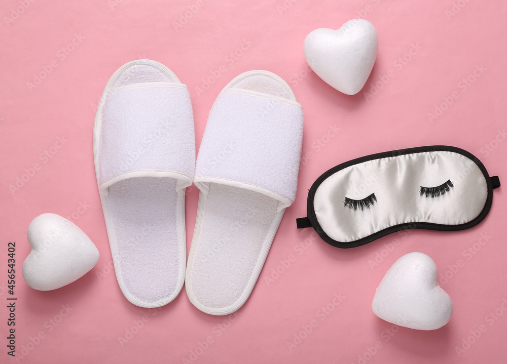 Sleeping mask with eyelashes, hearts and slippers on a pink background. Sweet, love dreams. Top view Sleeping mask with eyelashes, hearts and slippers on a pink background. Sweet, love dreams. Top view
