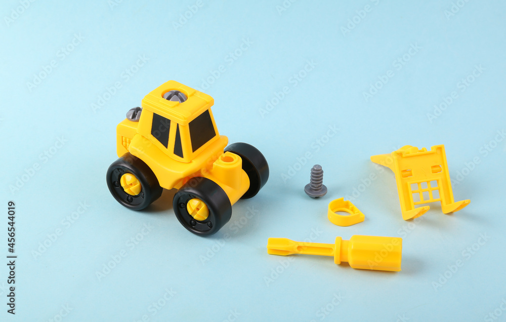 Fototapeta premium Disassembled toy loader on blue background. Renovation concept