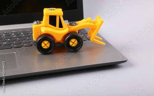 Laptop with toy loader on a white background. Delivery concept. Cargo transportation. Online shopping