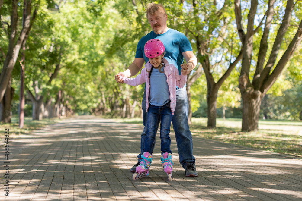 dad teaches daughter to roller skate. dad teaches daughter to roller skate.