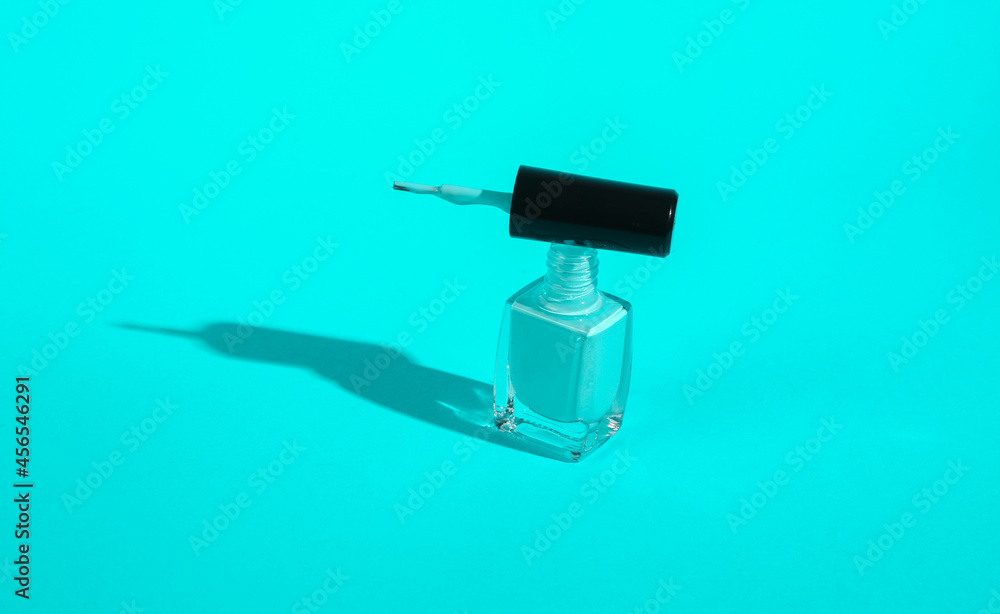 Bottle of turquoise nail polish on turquoise background. Minimal beauty concept Bottle of turquoise nail polish on turquoise background. Minimal beauty concept