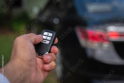 Hand of a man holding and push remote control of black car, technology transportation safety concept